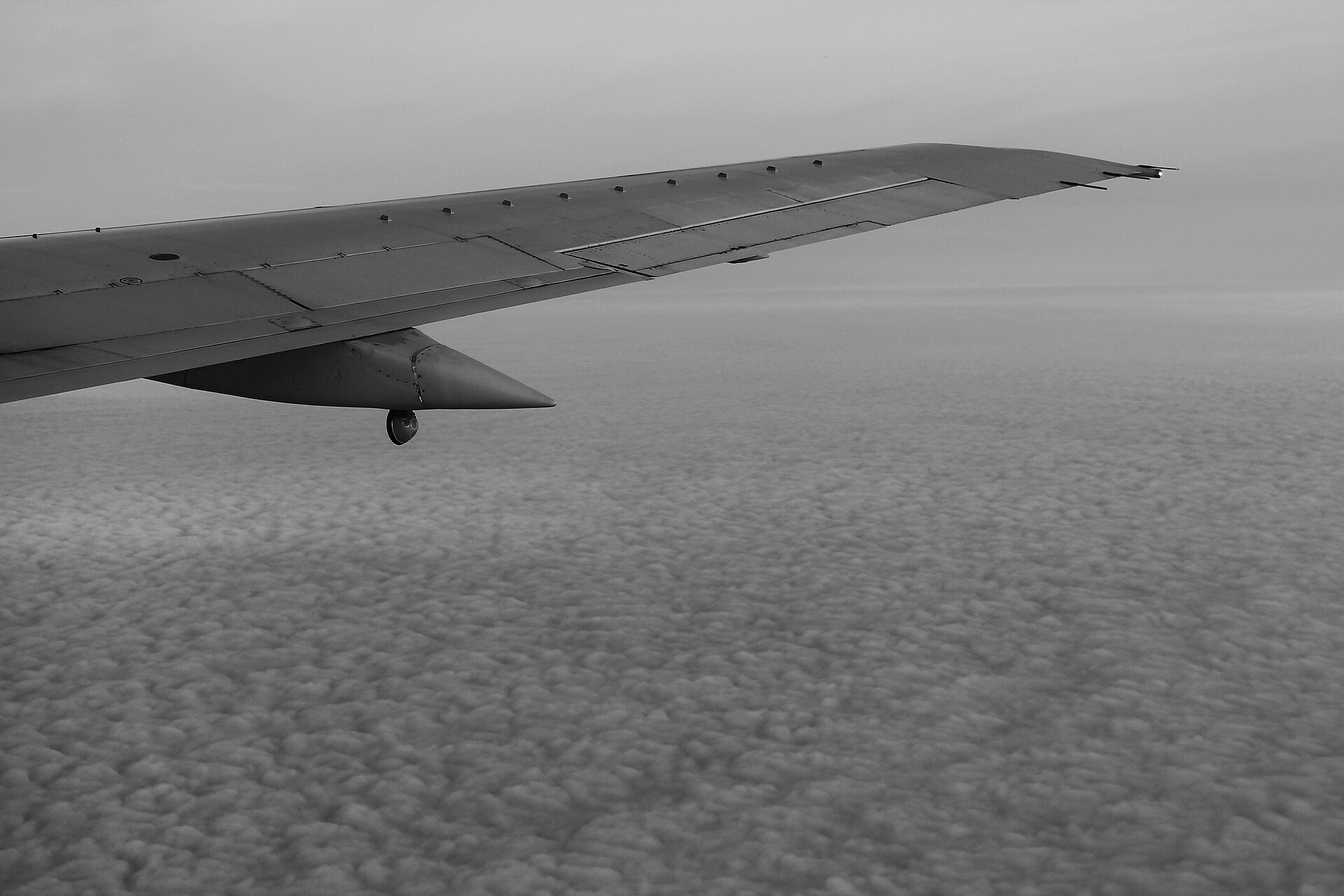 An aircraft wing over a sea of puffy clouds